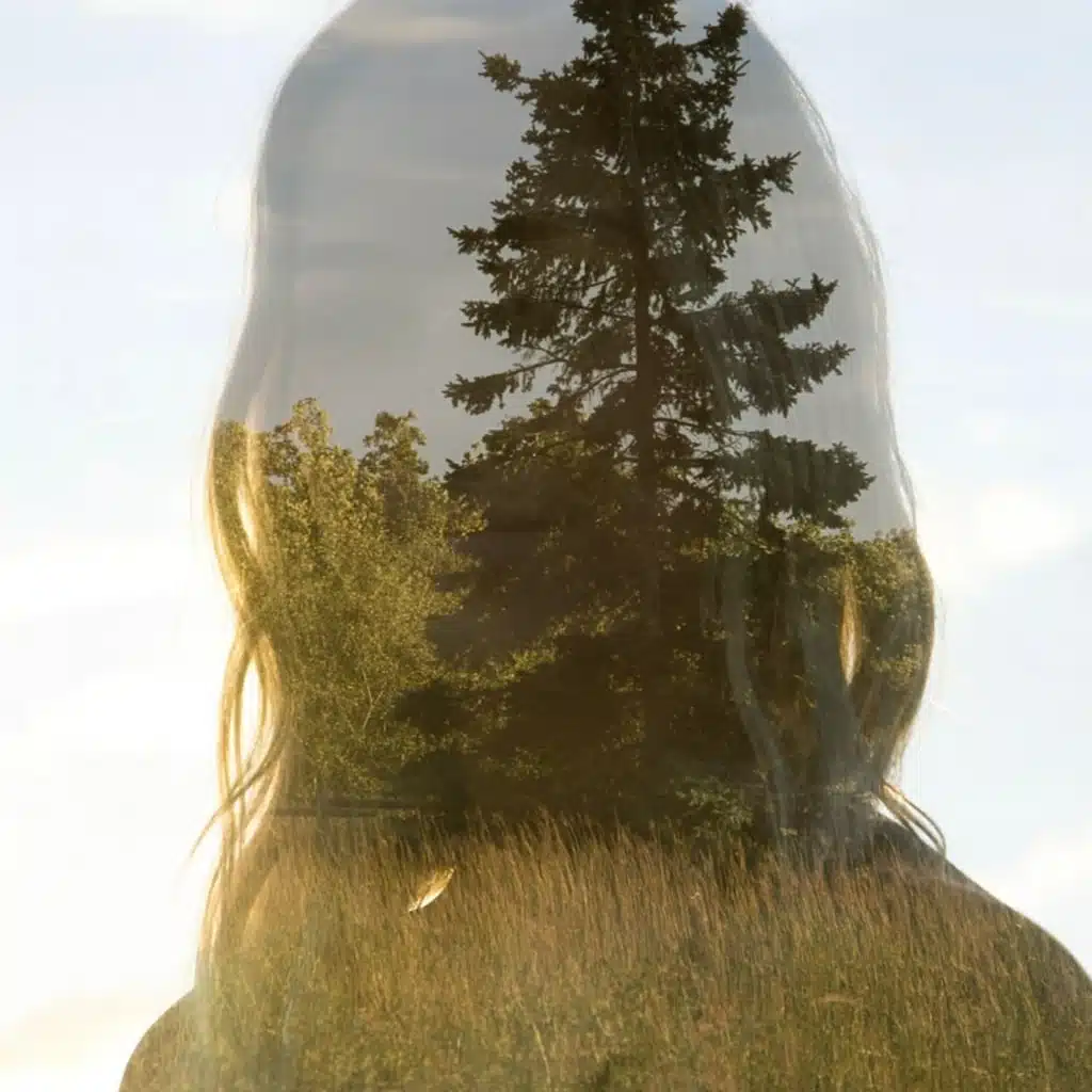 Silhouette de femme en double exposition avec une forêt de sapins, symbole de santé mentale et connexion à la nature.