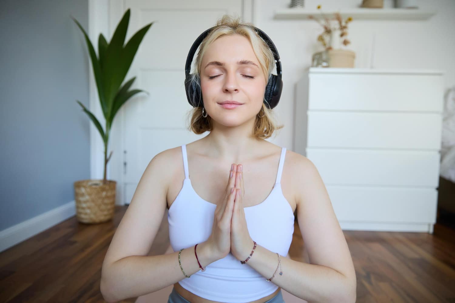 Jeune femme pratiquant une séance de sophrologie audio au casque pour une immersion totale dans la relaxation à domicile.