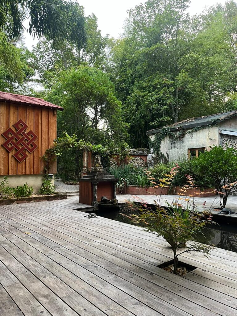 Espace de méditation extérieur avec nœud sans fin bouddhiste, bambous et petit étang de jardin pour une séance de sophrologie
