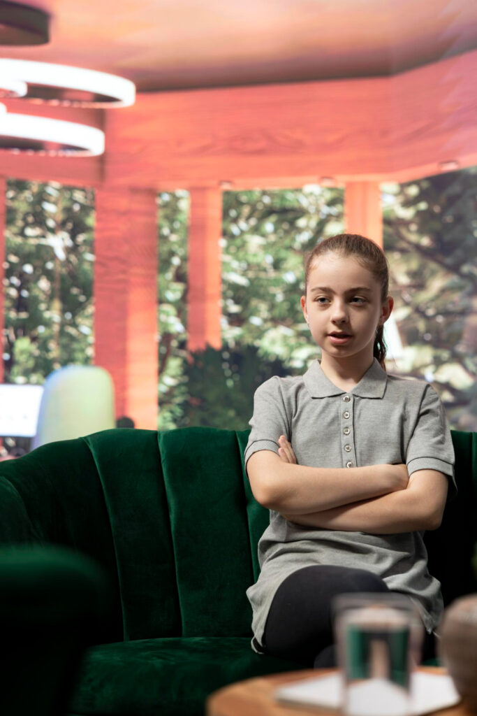 Enfant en séance de sophrologie pour apprendre à gérer ses émotions et son stress, assise sur un canapé vert.