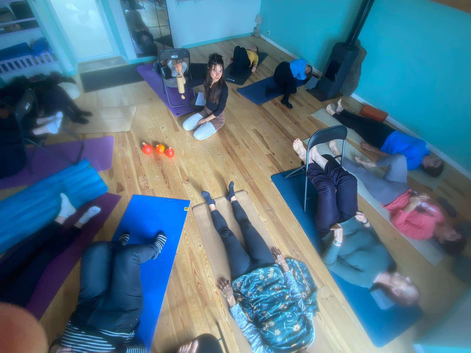 Séance de sophrologie collective en cabinet, participants allongés sur des tapis de yoga en relaxation profonde sous la guidance d'une sophrologue certifiée.